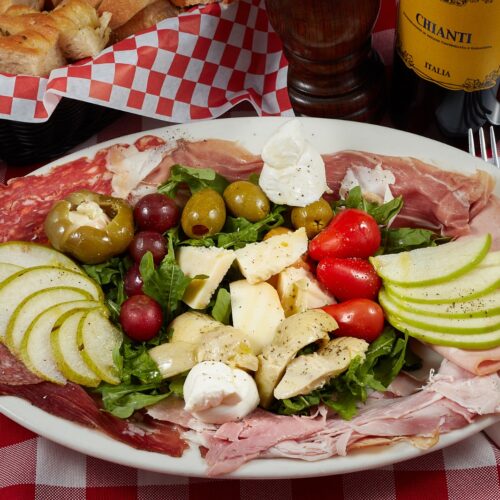 Antipasto Misto: array of cold cuts, prosciutto, mortadella, speck, salame, sliced apple, pear, grapes, cheese, cherry tomatoes, olives, artichokes, Arugula.